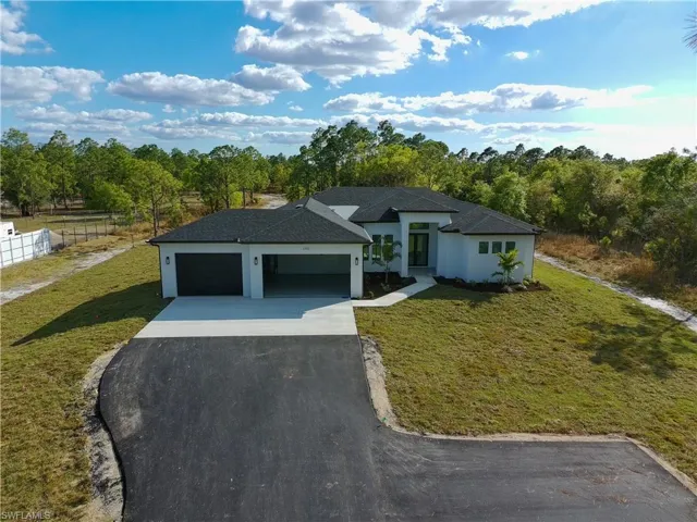 View of front of property featuring a front lawn, asphalt driveway, a garage, and stucco siding
