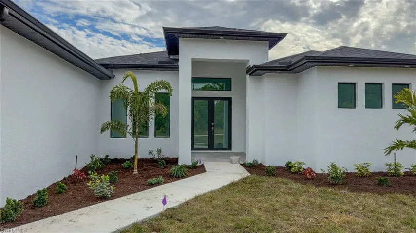 Doorway to property with stucco siding, a shingled roof, a lawn, and french doors