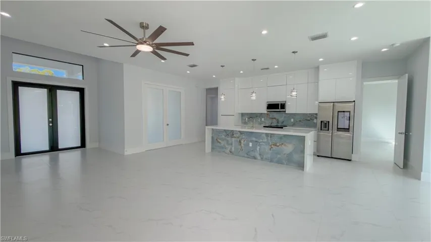 Kitchen with modern cabinets, stainless steel appliances, light marble finish floors, white cabinetry, and a spacious island