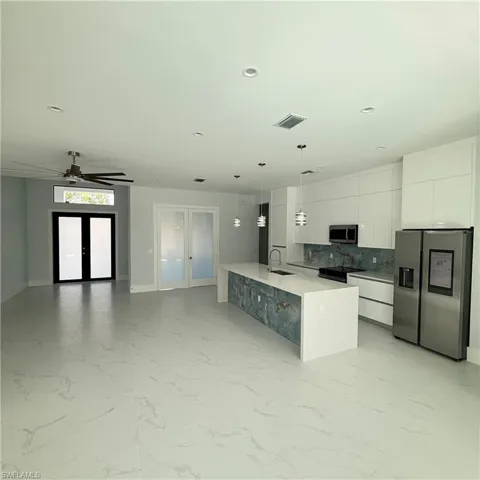 Kitchen with stainless steel appliances, modern cabinets, french doors, hanging light fixtures, and open floor plan