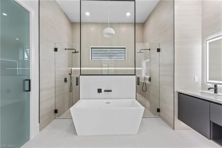 Full bathroom with a shower stall, vanity, a soaking tub, light tile patterned floors, and tile walls