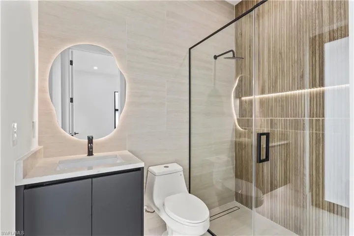 Bathroom featuring tile walls, vanity, and a stall shower