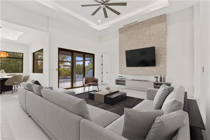 Living room with a tray ceiling, ceiling fan, a high ceiling, and recessed lighting