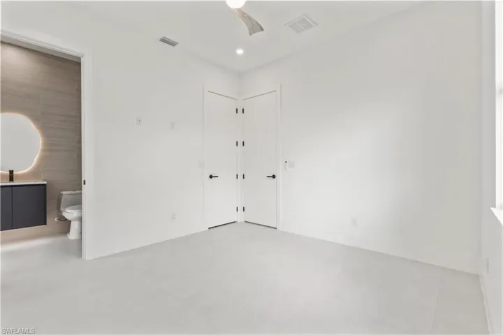 Unfurnished bedroom featuring ceiling fan, connected bathroom, and tile patterned floors