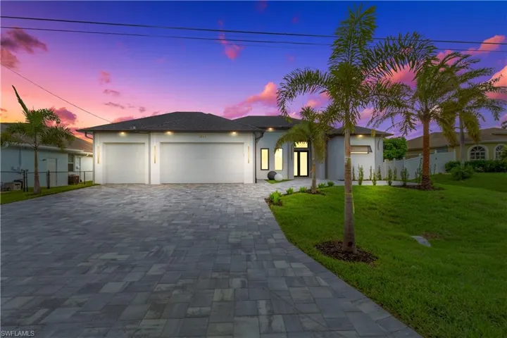 View of front of property featuring an attached garage, decorative driveway, and stucco siding