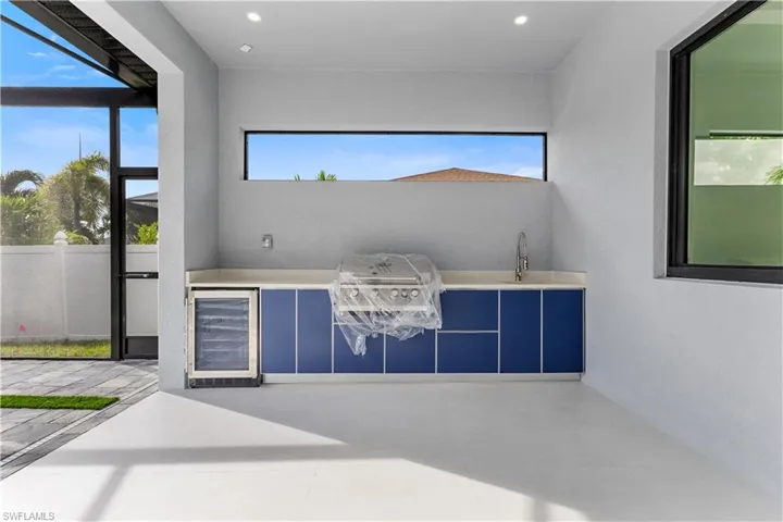 View of patio featuring wine cooler, a sunroom, and grilling area