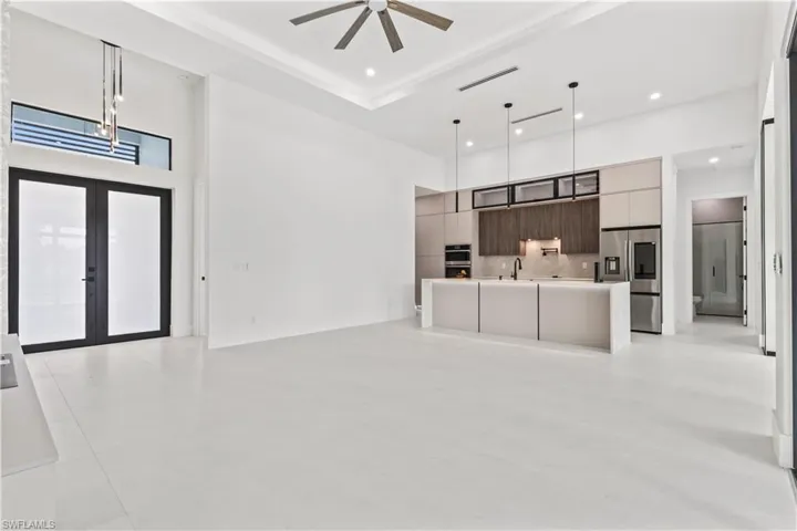 Unfurnished living room featuring a towering ceiling, french doors, light tile patterned floors, and recessed lighting