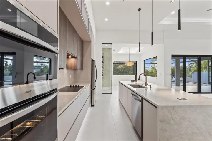 Kitchen with appliances with stainless steel finishes, modern cabinets, pendant lighting, light stone counters, and recessed lighting