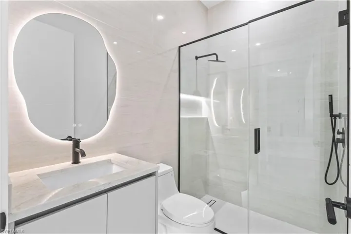 Full bath with vanity, a stall shower, and tile walls