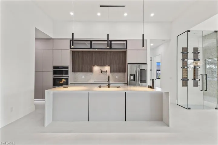 Kitchen with a center island with sink, modern cabinets, appliances with stainless steel finishes, light stone counters, and recessed lighting
