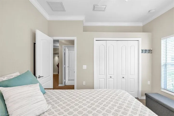 White bi-fold closet doors, crown molding, white trim, recessed lighting, and a window with blinds