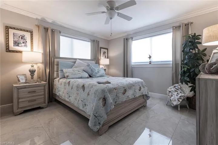 Bedroom with marble finish floor, baseboards, crown molding, and a ceiling fan
