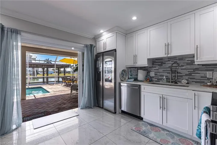 Kitchen with decorative backsplash, light countertops, ornamental molding, stainless steel appliances, and a sink