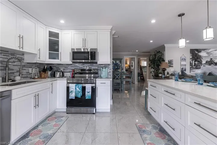 Kitchen with white cabinets, stainless steel appliances, tasteful backsplash, glass insert cabinets, and a sink