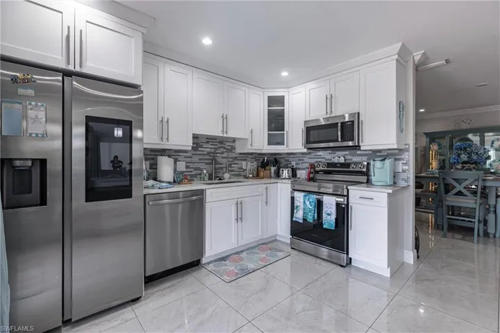 Kitchen featuring a sink, white cabinetry, light countertops, and appliances with stainless steel finishes