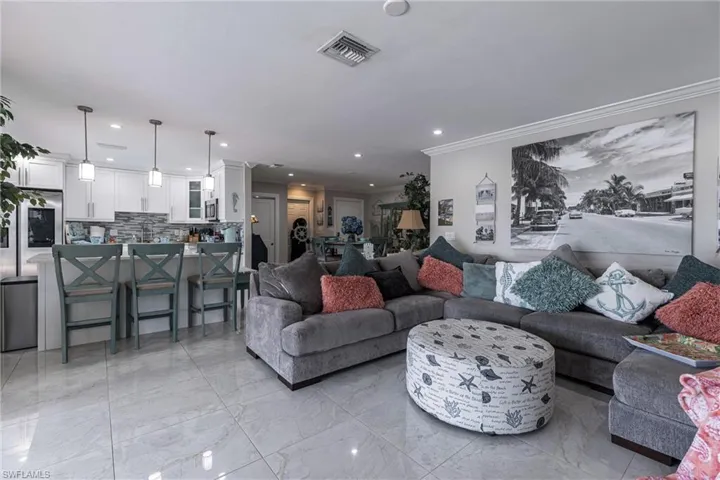 Living room with marble finish floor, recessed lighting, ornamental molding