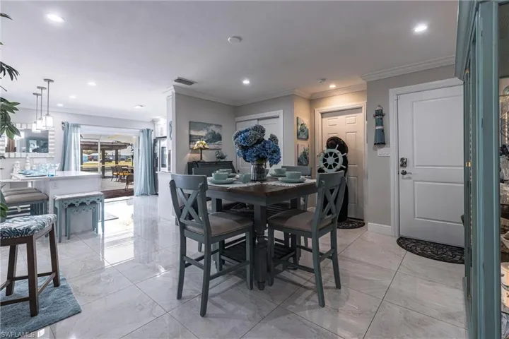Dining room with marble finish floor, recessed lighting, and crown molding