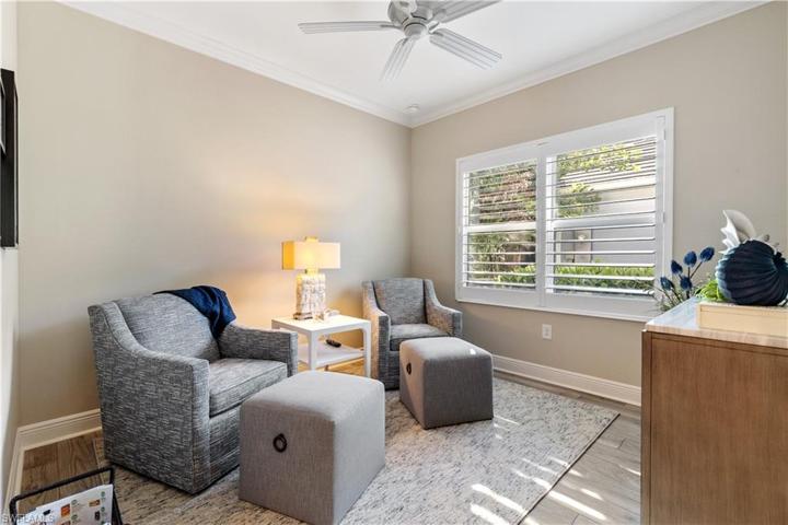 Cozy den with wood plantation shutters and mounted television that is included.