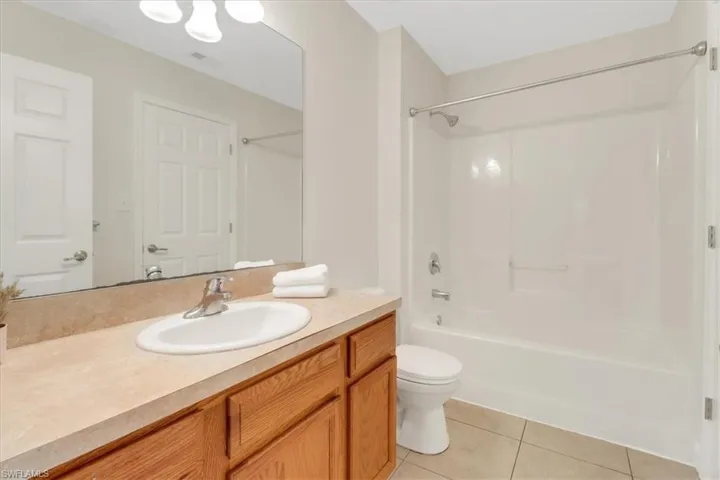 Bathroom with toilet, shower / tub combination, vanity, and tile patterned flooring