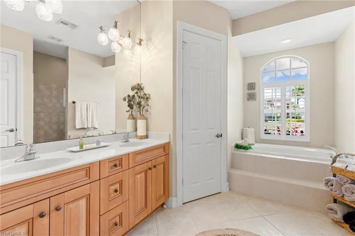 Full bathroom featuring a bath, a sink, visible vents, and double vanity