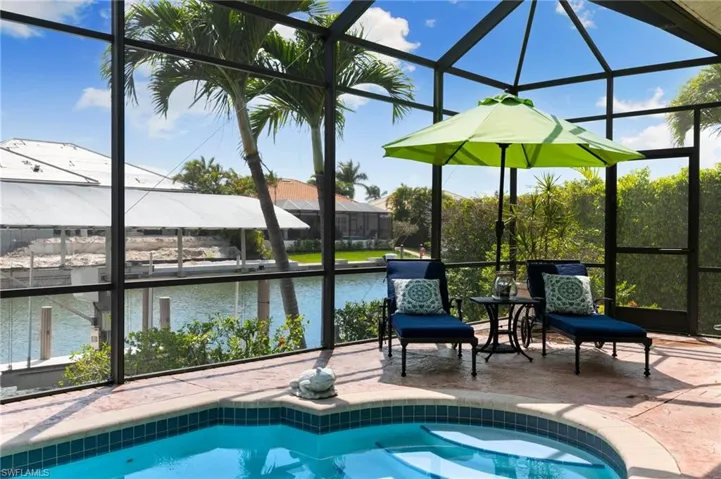 Outdoor pool with glass enclosure, a patio, and a water view
