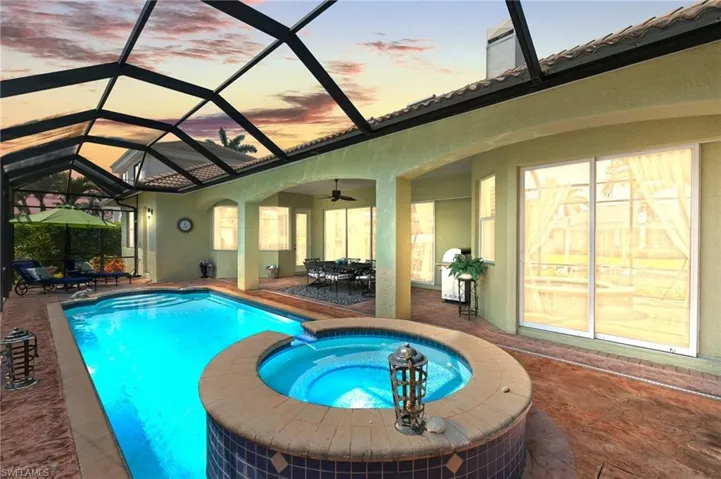 View of swimming pool featuring a lanai, outdoor dining area, a pool with connected hot tub, and a patio