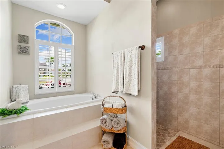 Full bathroom with a bath, a tile shower, and a wealth of natural light