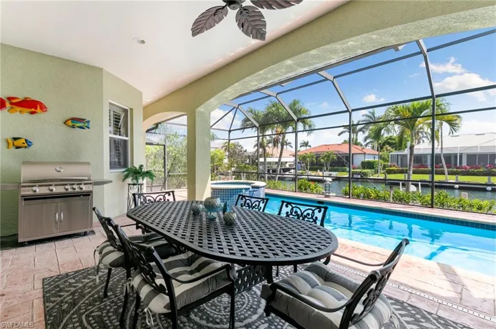 View of swimming pool featuring a water view, a ceiling fan, outdoor dining space, a grill, and a patio