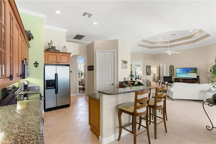 Kitchen with arched walkways, crown molding, appliances with stainless steel finishes, and light tile patterned floors