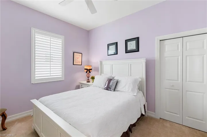 Bedroom with ceiling fan, light carpet, a closet, and baseboards