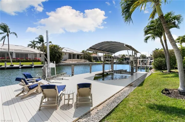 View of dock featuring a lawn, boat lift, and a water view