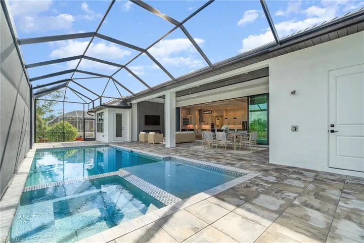 View of pool, spa and massive lanai including outside shower and storage closet for pool and boat gear