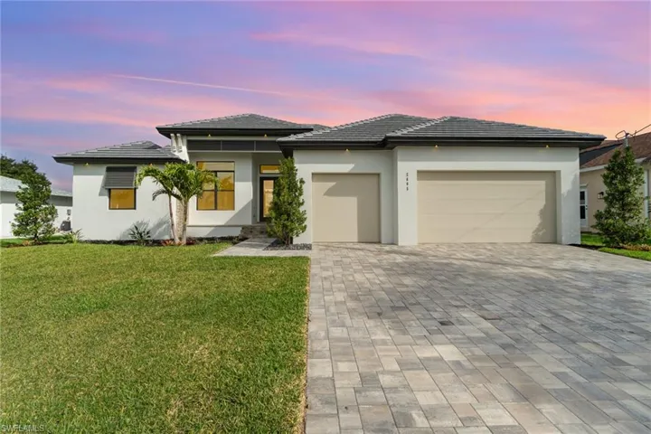 SW Florida sunset colors highlighting the beautiful home with paver driveway