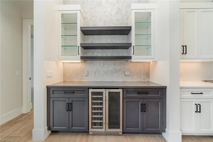 Wine bar featuring open shelves, glass insert cabinets, and wine cooler