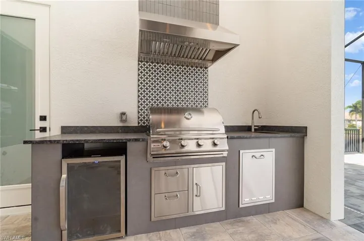View of beautiful summer kitchen with grill, sink and beverage refrigerator