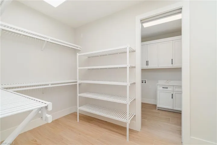 Huge walk in closet with wood tiled floors and convenient access to the laundry room