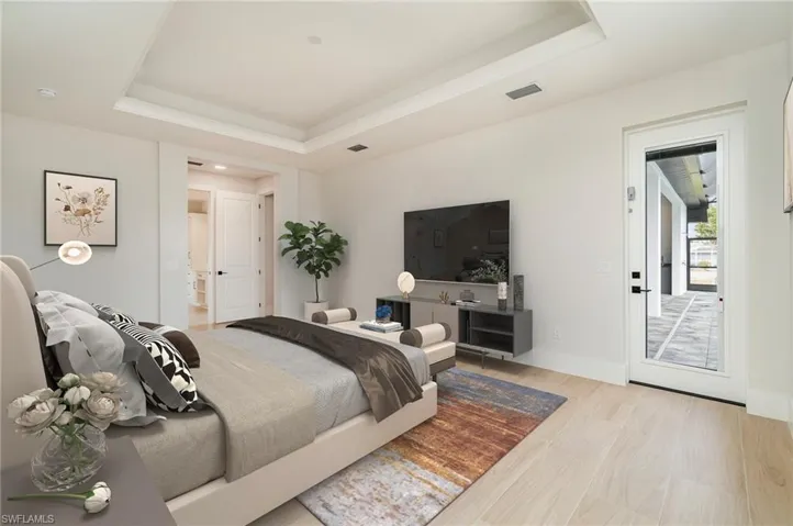 Master bedroom featuring a raised ceiling and light wood plank tile floors