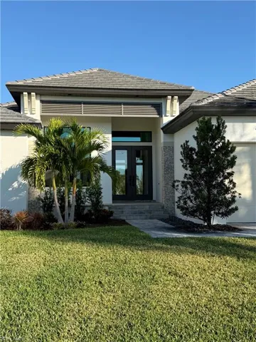 Property entrance with french doors, stucco siding, a yard, and a garage