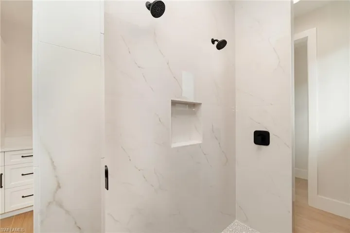 Master bath shower with a marble tile finish shower and two shower heads