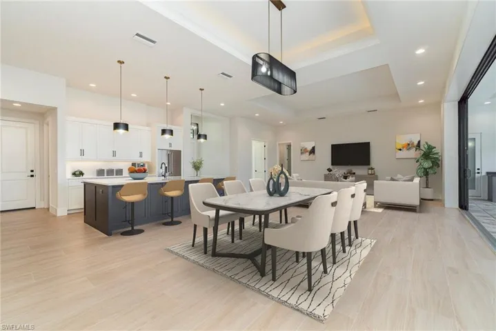 Dining space featuring a lighted tray ceiling, light wood plank tile flooring