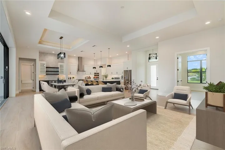 Living area with a tray ceiling, recessed lighting, and light wood plank tile flooring