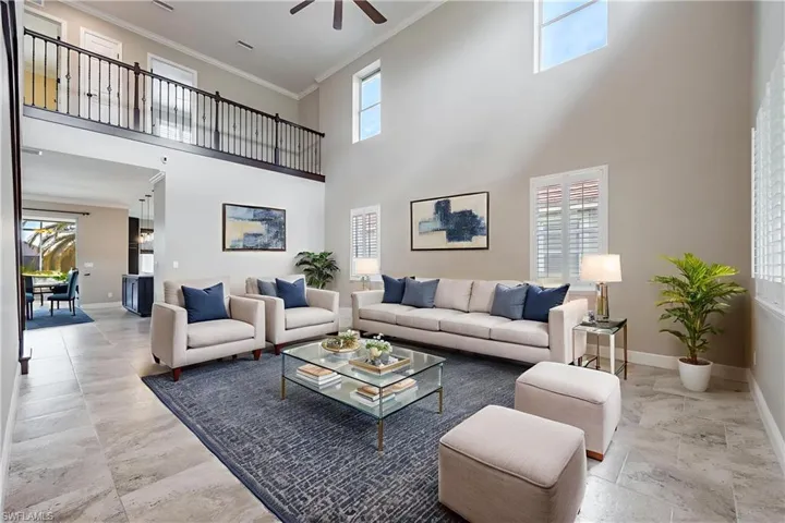 Living area featuring a ceiling fan, crown molding, and a high ceiling Virtually Staged