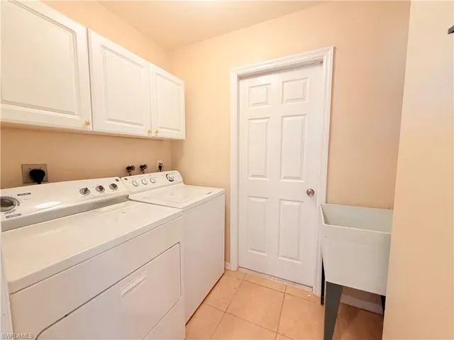Laundry room featuring light tile patterned floors, independent washer and dryer, and cabinet space
