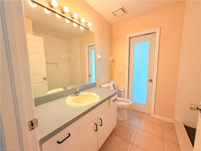 Bathroom with vanity, light tile patterned flooring, and a shower