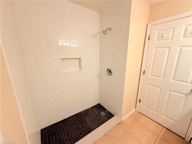 Full bath featuring a stall shower and light tile patterned flooring