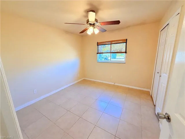 Unfurnished bedroom featuring a closet, light tile patterned flooring, and ceiling fan