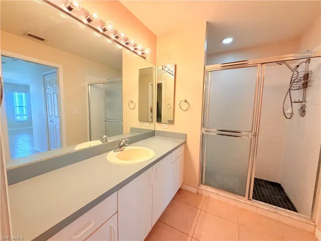 Full bath with a shower stall, vanity, and light tile patterned floors