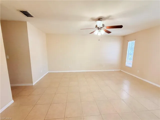 Empty room featuring ceiling fan and light tile patterned floors