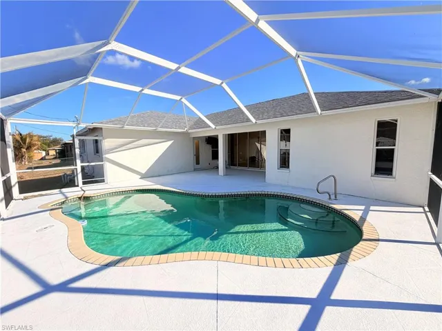 Outdoor pool featuring a sunroom, a patio, and glass enclosure