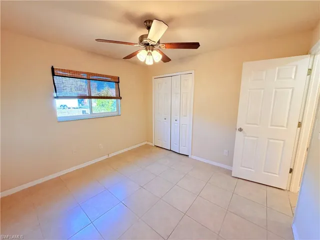 Unfurnished bedroom featuring ceiling fan, light tile patterned flooring, and a closet